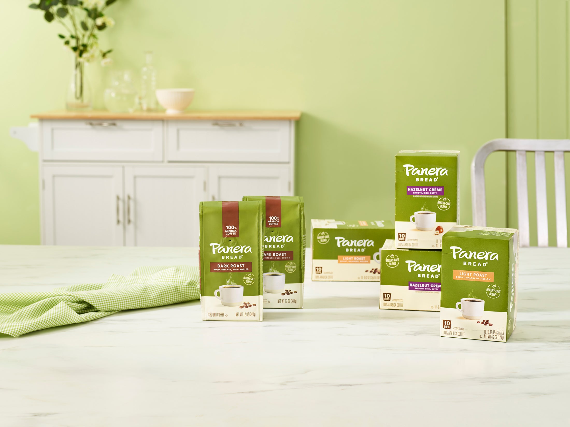 panera ground coffee and single serve cups on a dining room table with furniture in the background